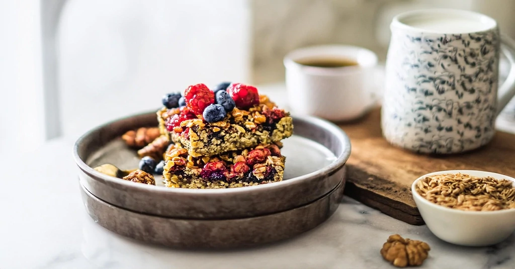 A close-up of Protein Baked Oatmeal topped with fresh berries and a drizzle of honey, served on a rustic plate with a fork beside it.