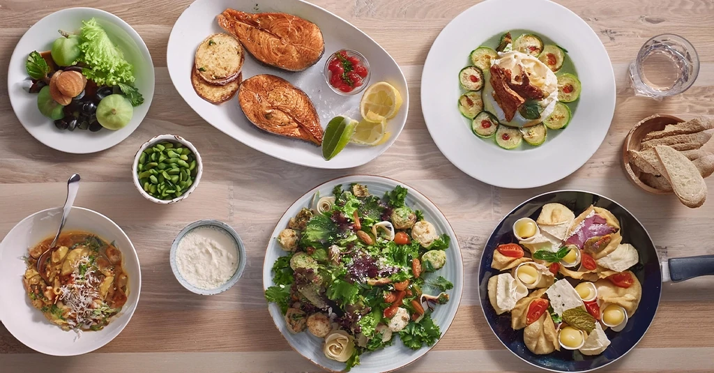 Top view of a modern kitchen table filled with many recipes and dishes, showcasing a variety of meals ready for family meal planning.